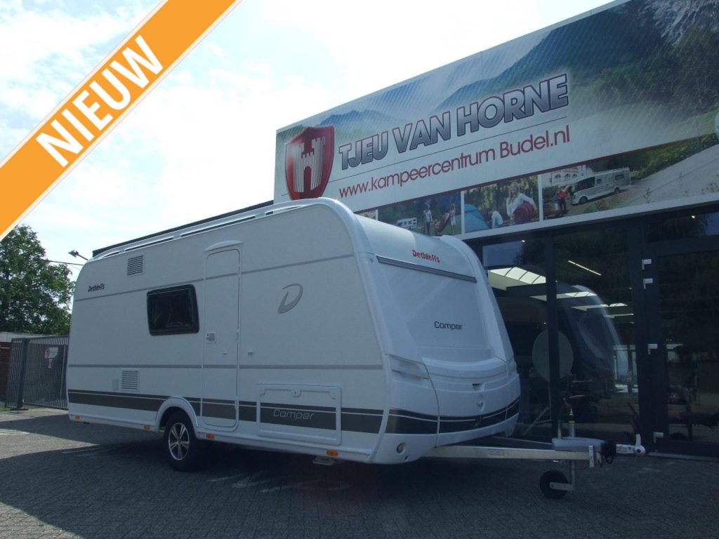 Trotse caravaneigeaar bereidt caravan voor vakantie voor met doekje schoon maken
